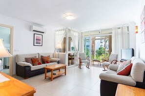 A modern living room with a sofa, coffee table, and chairs, a television, and a balcony with a view. - Carabeo 10 by Casasol (Nerja)