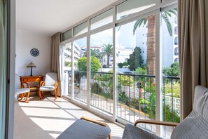 En balkon med sofa, stol og skrivebord med lampe.
