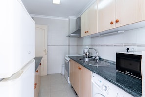 A modern kitchen with white cabinets, a stainless steel sink, a built-in oven, and a dishwasher. - Carabeo 10 by Casasol (Nerja)
