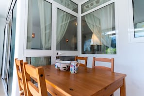 Un coin repas avec une table en bois, quatre chaises et une porte blanche dotée de panneaux de verre.