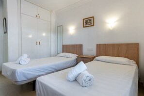 A hotel room with two single beds, a wooden headboard, a nightstand, a mirror, and a framed picture on the wall. - Carabeo 10 by Casasol (Nerja)