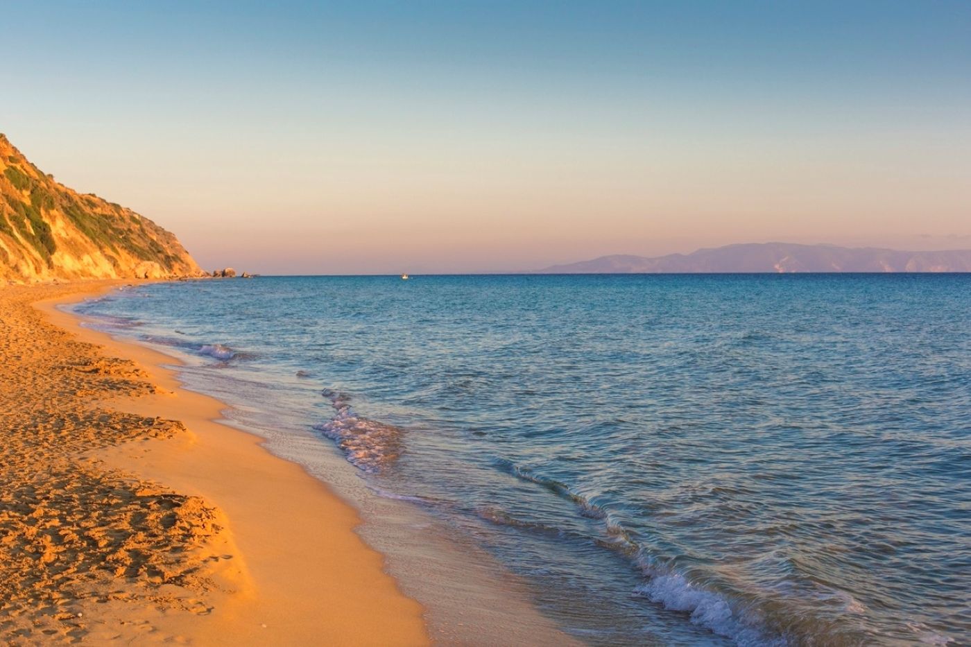 A beach with clear water and a sandy shore.