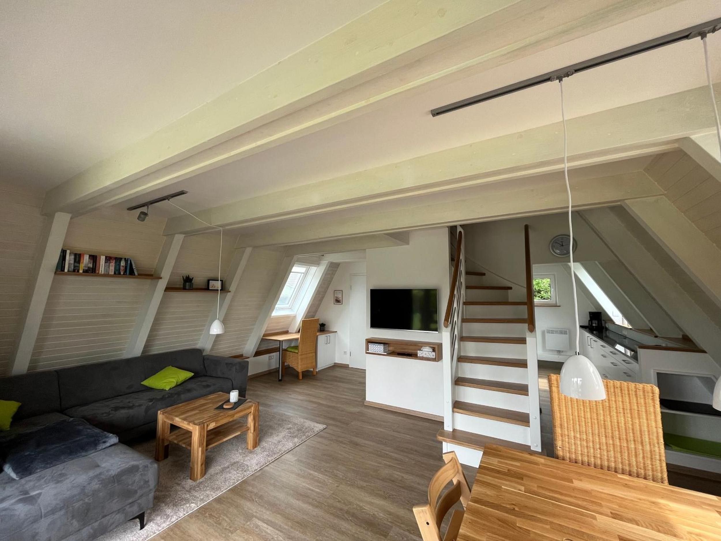 Ein großzügiges Loft mit hohen Decken, einer Treppe, einem Flachbildfernseher und einem Essbereich.