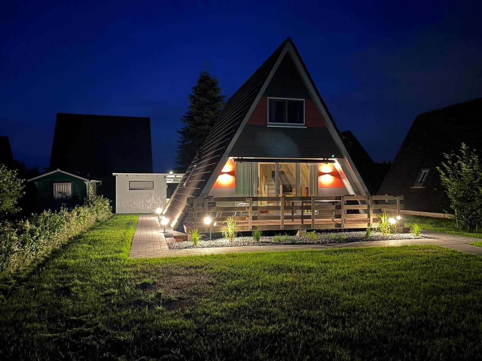 Ein modernes Haus mit geneigtem Dach, großen Fenstern und einer Holzterrasse.
