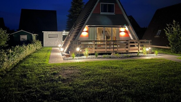 Una casa moderna con tetto spiovente, ampie finestre e un patio in legno.