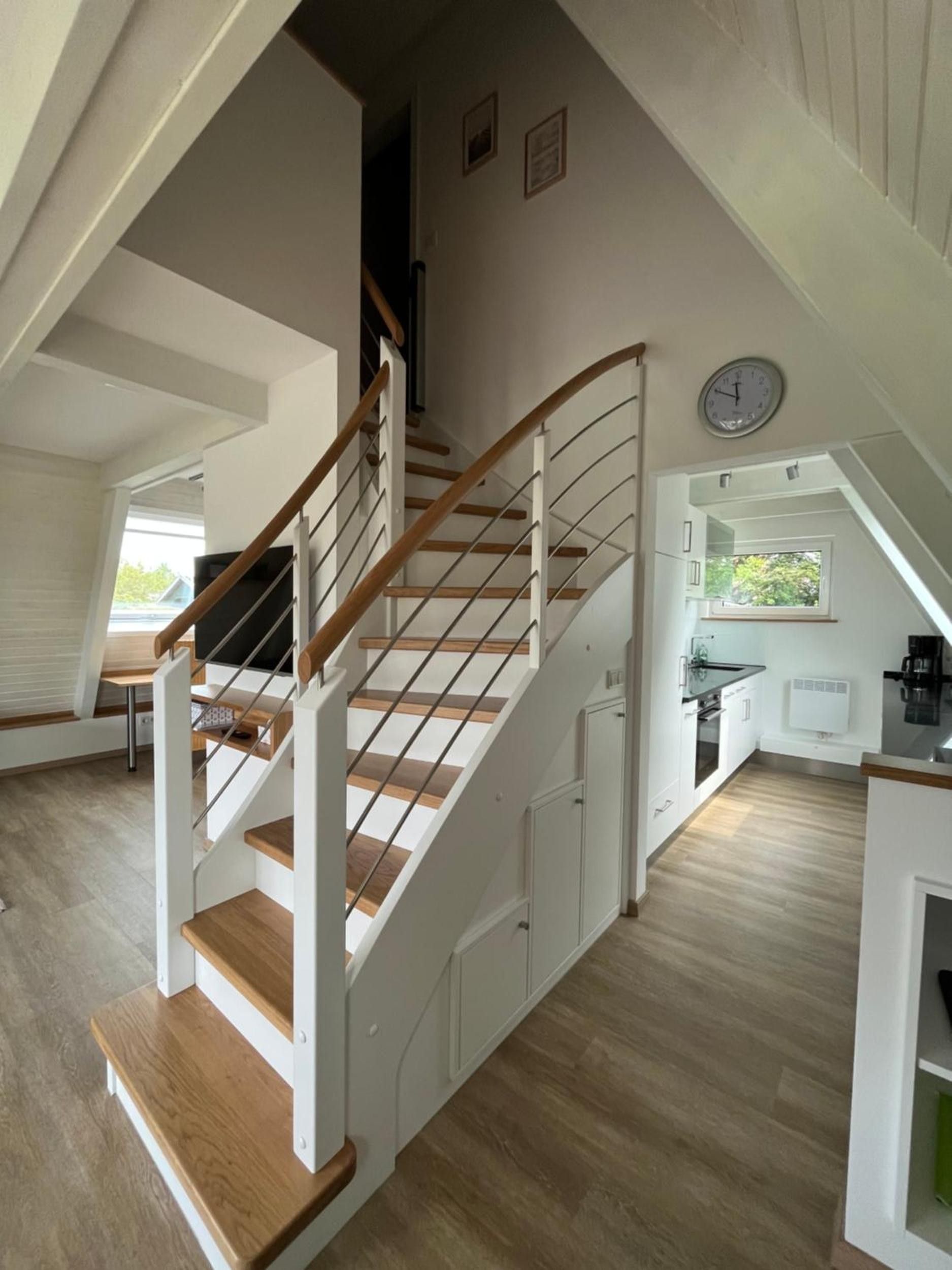 Ein modernes Interieur mit einer Holztreppe, weißen Wänden und einer Küchenzeile.