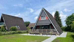 Una casa moderna con tetto spiovente, un patio in legno e un vialetto lastricato che conduce all'ingresso.