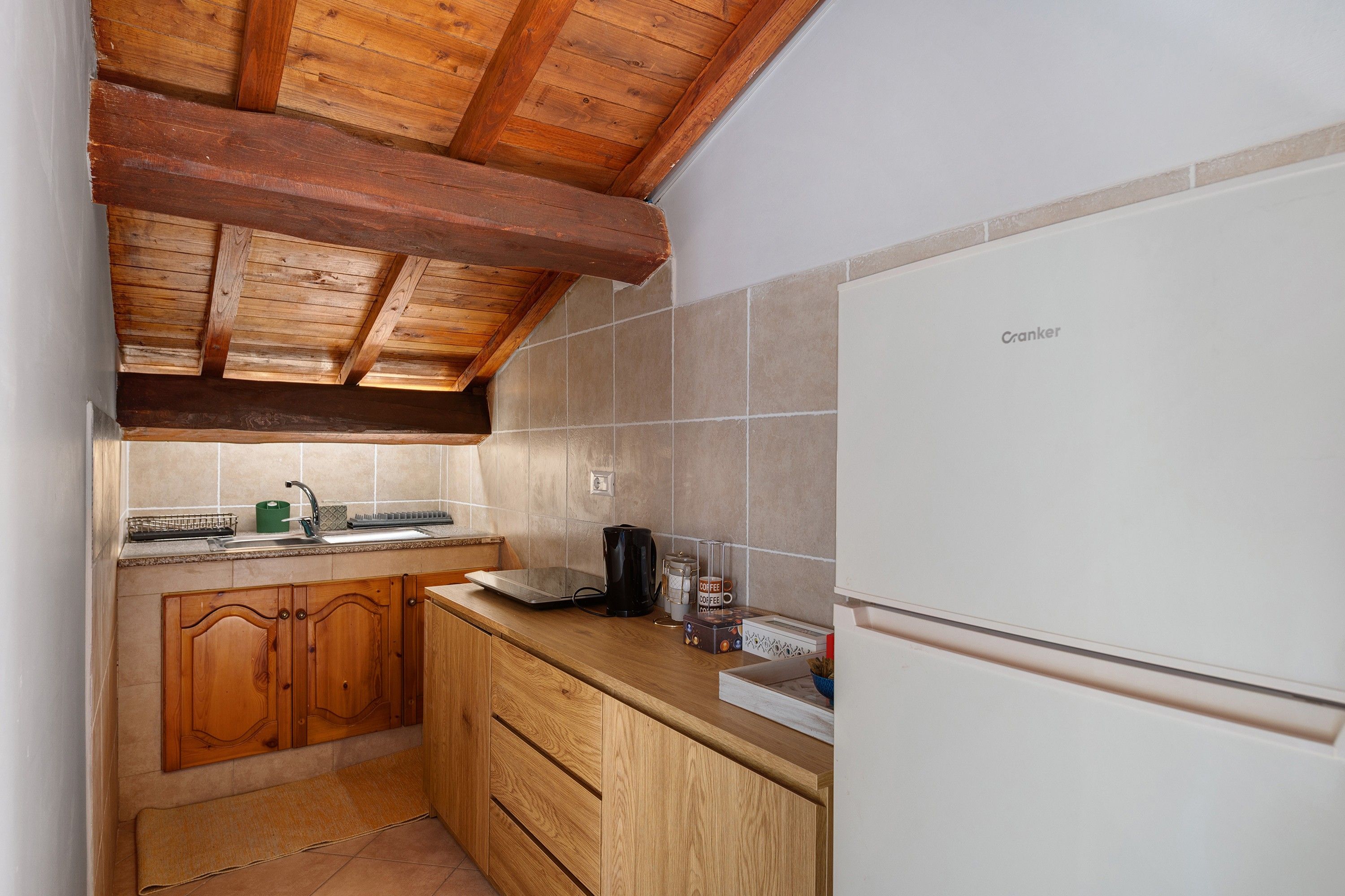 Une cuisine compacte avec des meubles en bois, un réfrigérateur blanc et un pare-feu en carrelage.