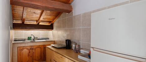 A compact kitchen with wooden cabinets, a white refrigerator, and a tiled backsplash.