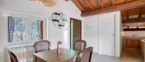 A dining area with a wooden table, four chairs, a vase with a flower, and a wall-mounted wine rack.