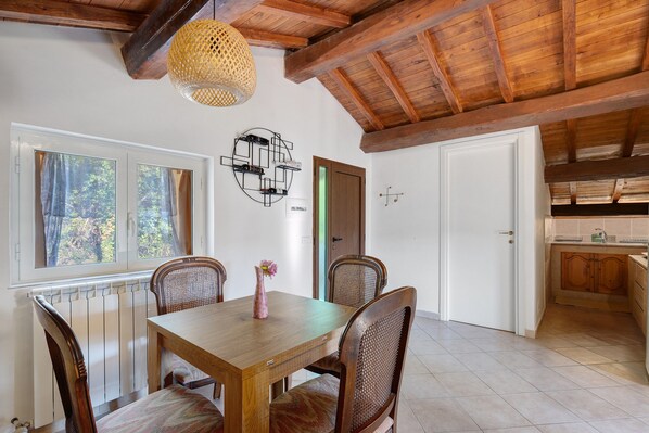 A dining area with a wooden table, four chairs, a vase with a flower, and a wall-mounted wine rack.