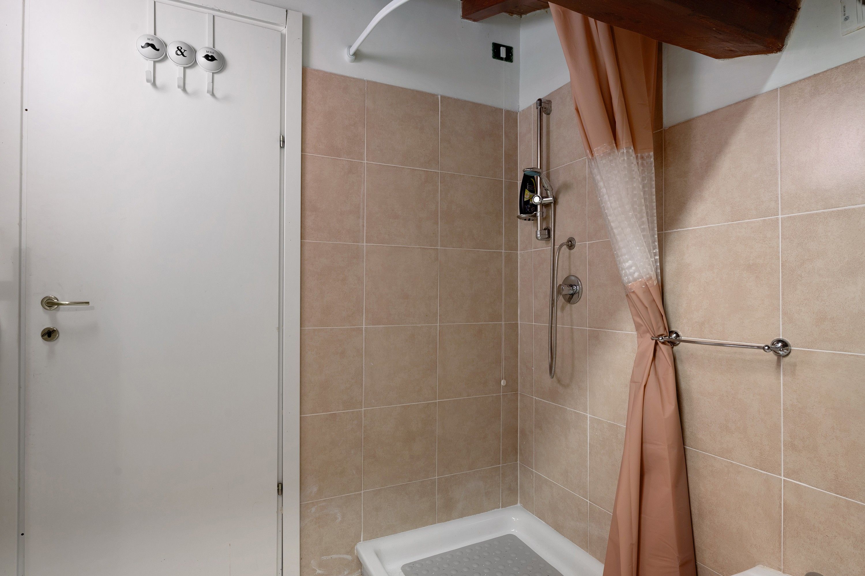 Ein Duschbereich mit Duschvorhang, Handbrause und am Wand montierter Armatur.