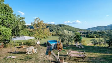 An outdoor setting with a pool, lounge chairs, and a table with chairs.