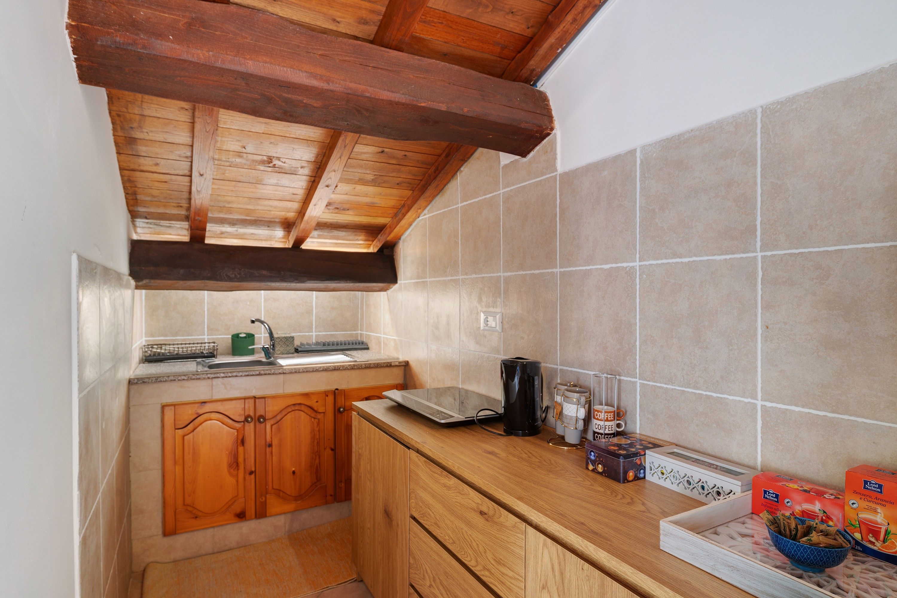 Una cucina funzionale con mobili in legno, zoccolo paraschizzi piastrellato e macchina per il caffè.
