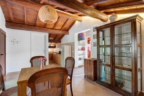 A dining area with a wooden table and chairs, a cabinet with glass doors, and a hanging light fixture. - Holiday Home 'Soggiorno dell'artista' with Lake View, Wi-Fi and Air Conditioning (Terni)