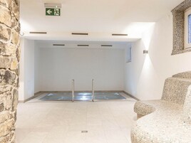 A room with a pool, stone wall, and a green exit sign.