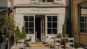 A building with a sign reading 'Arberge Laplace' and a number '11' indicating its address. There are outdoor seating areas with chairs and tables.