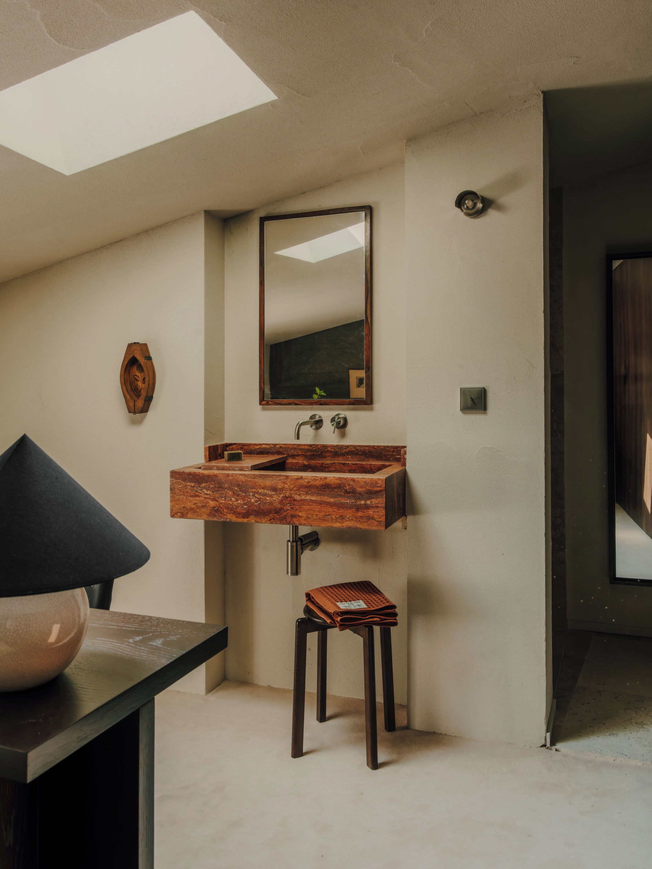 A bathroom with a wooden vanity, a mirror, and a small stool.