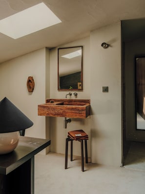 Une salle de bain avec un meuble-lavabo en bois, un miroir et un petit tabouret.