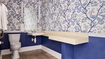 A bathroom with a toilet, sink, and blue floral wallpaper.