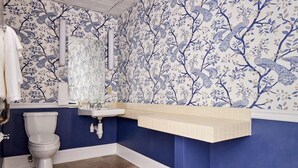 Een badkamer met toilet, wastafel en blauw behang met bloemen.