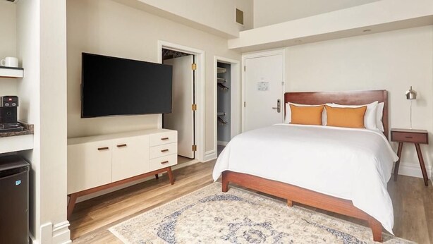 Een slaapkamer met een bed, een televisie, een kledingkast en een klein tafeltje.