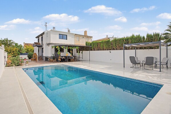 Une piscine rectangulaire à l’eau d’un bleu limpide, entourée d’une terrasse aménagée avec des meubles d’extérieur.
