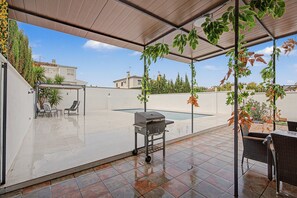 Une terrasse extérieure équipée d’un barbecue, de sièges et d’une piscine.