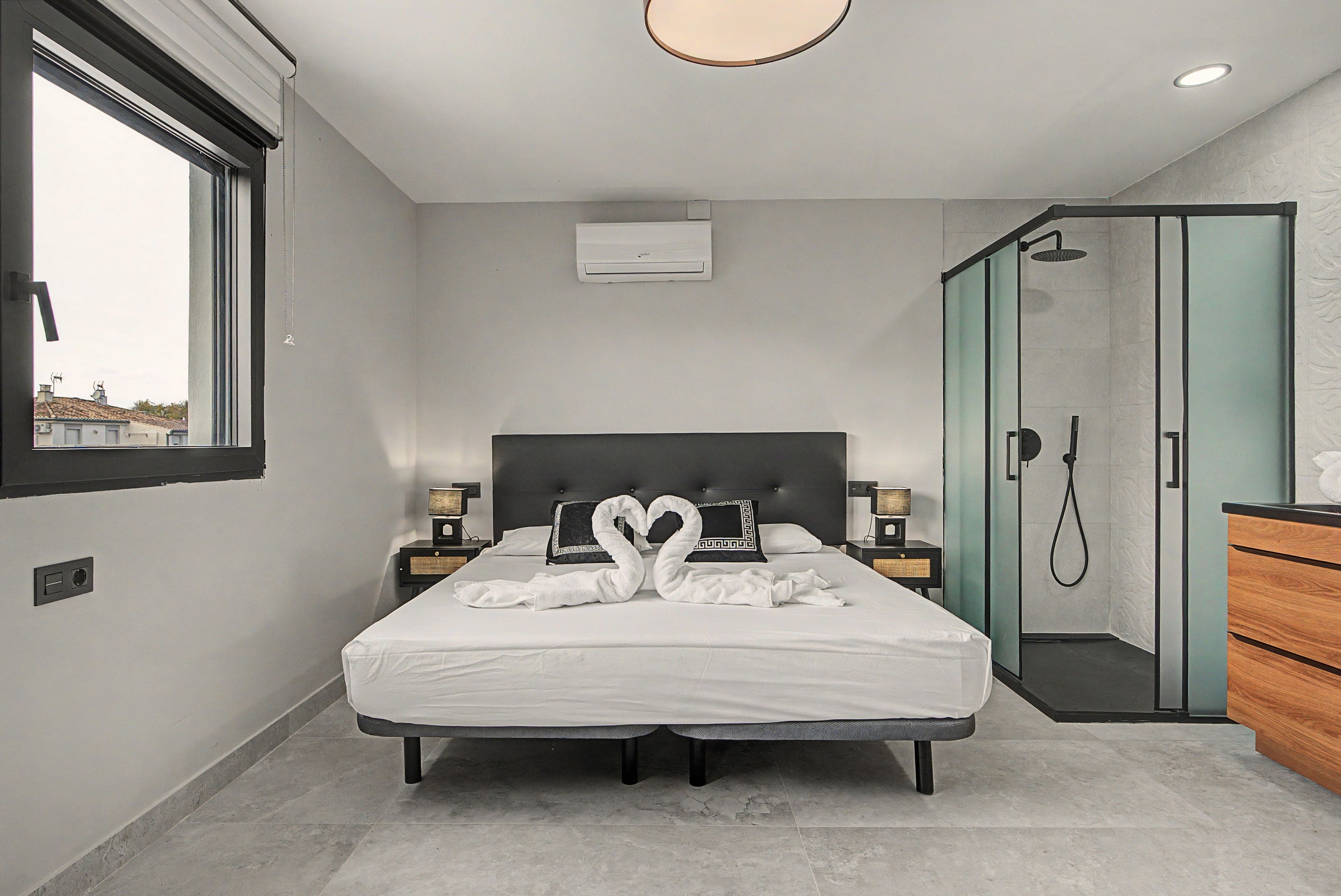 Een moderne hotelkamer met een groot bed, een inloopkast en een badkamer met douche.