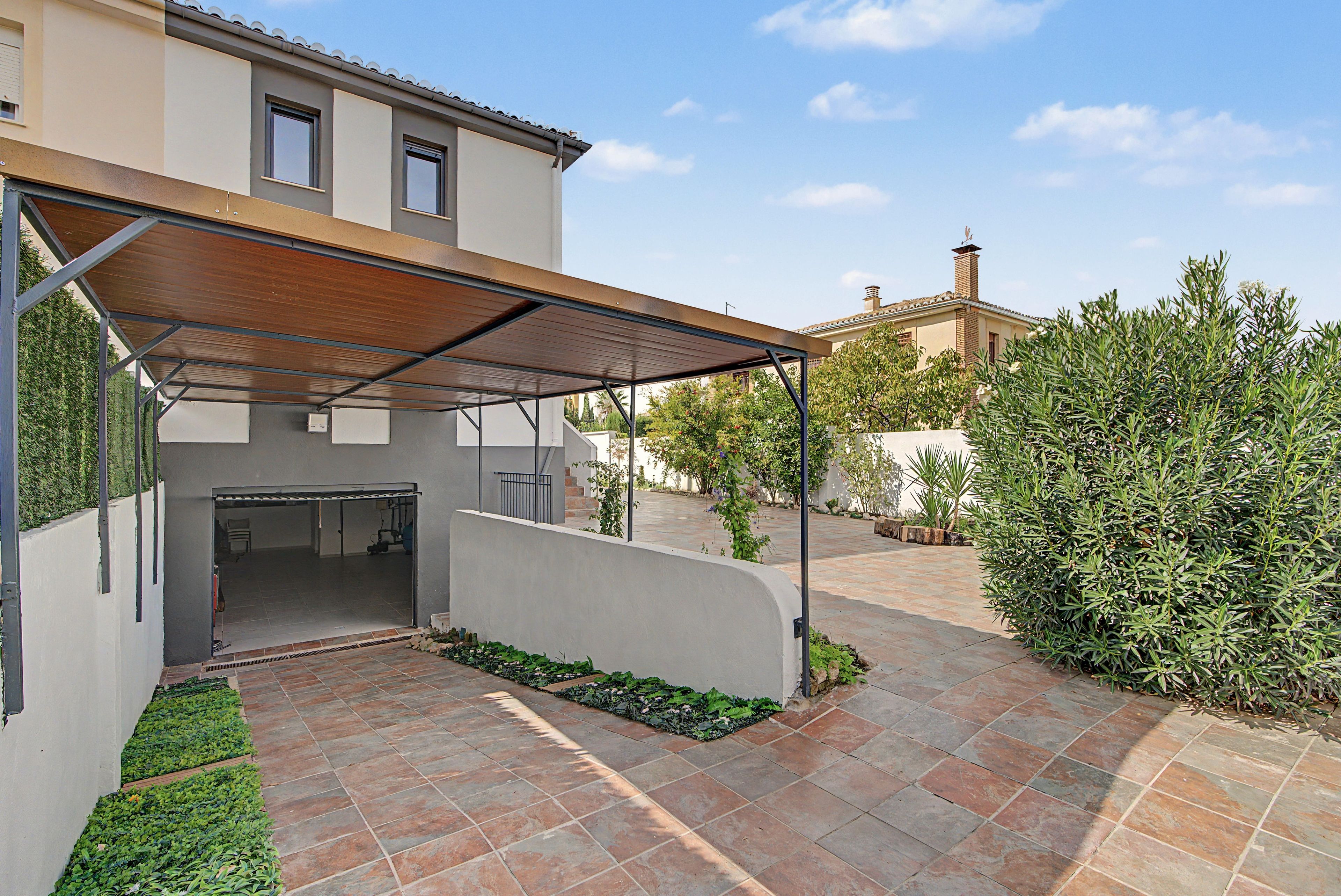 A covered outdoor area with a patio, a wall, and a building in the background.