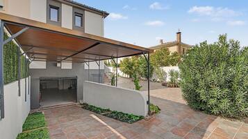 A covered outdoor area with a patio, a wall, and a building in the background.