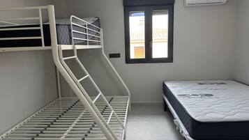 A room with bunk beds, a window, and an air conditioning unit.