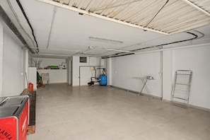 A spacious room with a tiled floor, a blue gas cylinder, and a metal rack.