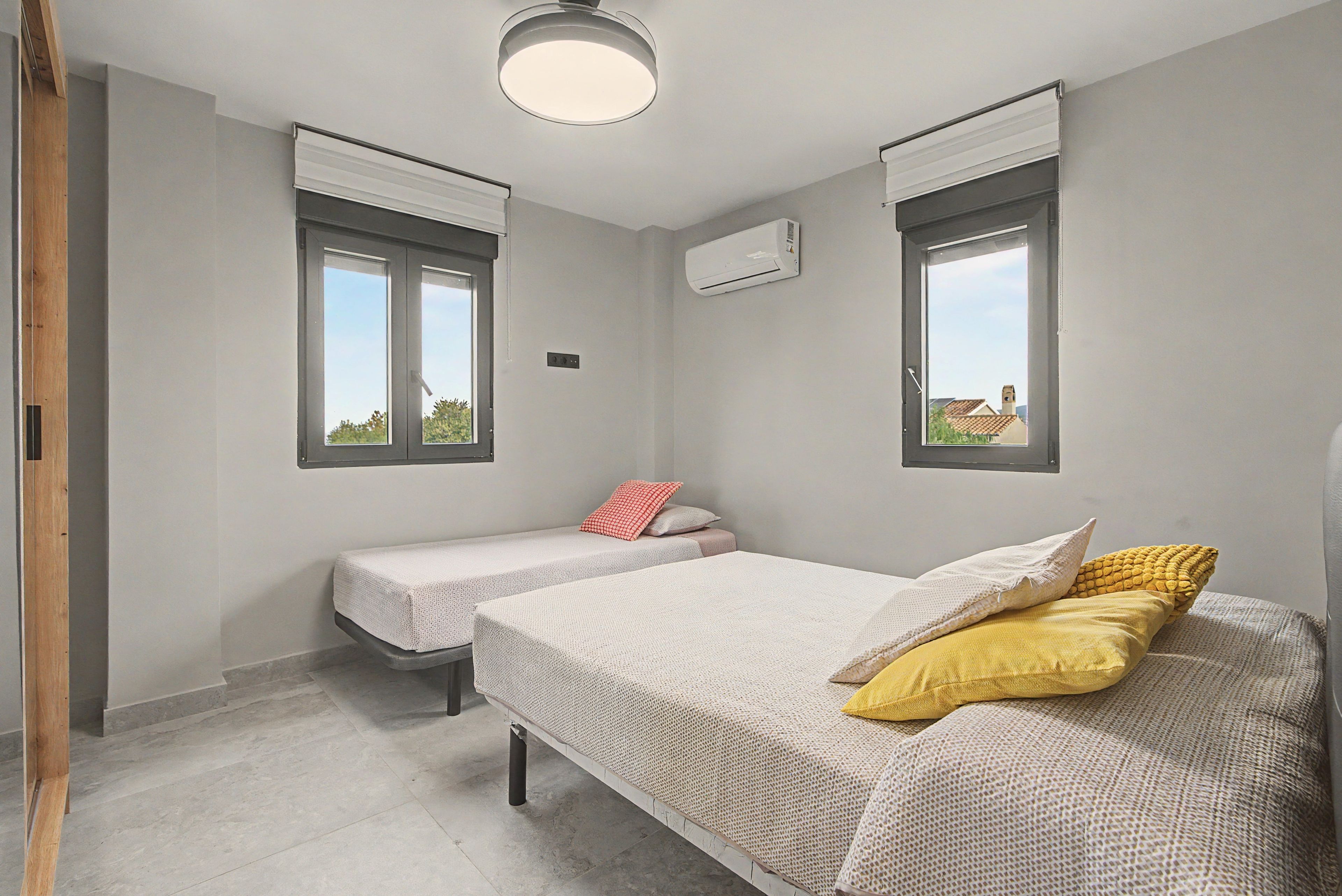 Une chambre avec deux lits, une fenêtre et un appareil de climatisation.