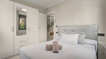 A bedroom with a bed, a wardrobe, and a bathroom visible through an open door.