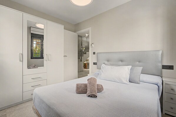 A bedroom with a bed, a wardrobe, and a bathroom visible through an open door.