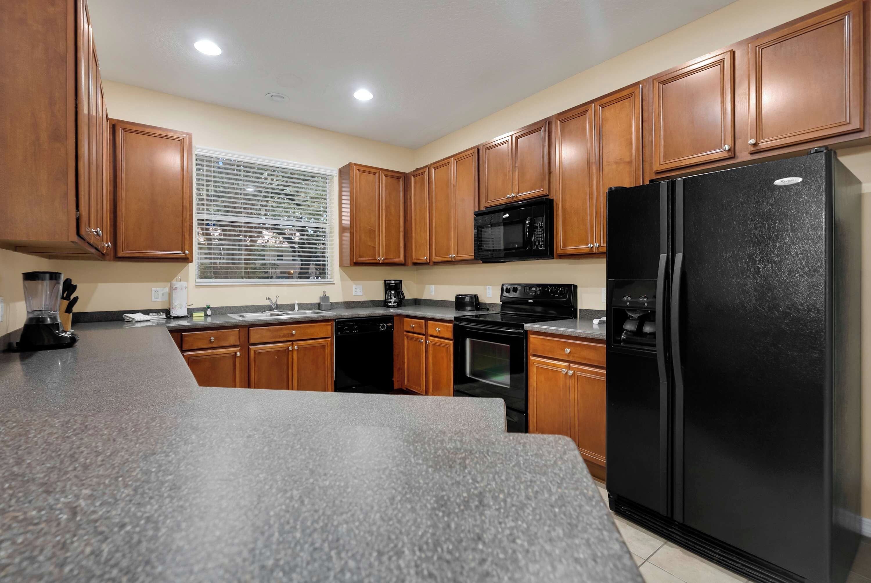 A kitchen with wooden cabinets, a black refrigerator, a microwave, and a dishwasher.