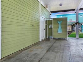 A covered porch with a green exterior wall, a white door, and a sign that reads 'Welcome.'