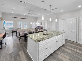 A spacious kitchen with a large island, pendant lighting, and a view to the outside.