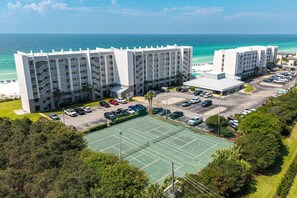 A multi-story hotel with a parking lot and a tennis court. - Beach House 601a 2 Bedroom Condo (Miramar Beach)