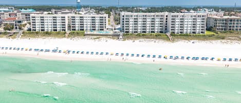 Un hotel frente a la playa con varias edificaciones, una playa arenosa y aguas turquesas cristalinas.