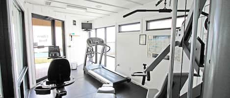 A gym with exercise equipment, a treadmill, and a weight bench.
