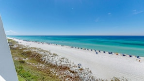 A beach with white sand, clear turquoise water, and a row of umbrellas. - Beach House 601a 2 Bedroom Condo (Miramar Beach)