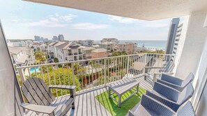 A balcony with outdoor furniture, a view of a residential area, and a body of water in the distance. - Mainsail 352 3 Bedroom Condo (Miramar Beach)