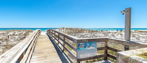 A wooden boardwalk leading to a beach with a sign about sea turtle nesting.