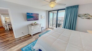 A bedroom with a bed, a dresser, a television, and a view of the outdoors through a sliding glass door. - Mainsail 352 3 Bedroom Condo (Miramar Beach)