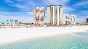 Ein Strandhotel mit mehreren Hochhäusern, blauem Himmel und einem Sandstrand.