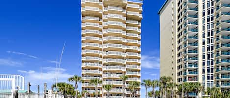 Un grand hôtel à plusieurs étages, doté de balcons, situé près d’une plage de sable.