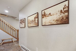 A staircase with wooden railings leading to a landing where three sepia-toned photographs are displayed on the wall. - Creekside Frisco Retreat 4 Private Suites, Pool & Hot Tubs 4 Bedroom Condo (Frisco)