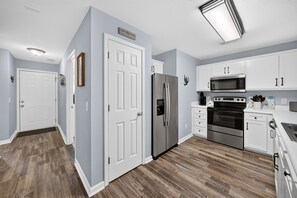 Eine moderne Küche mit weißen Schränken, Edelstahlgeräten und Holzboden.